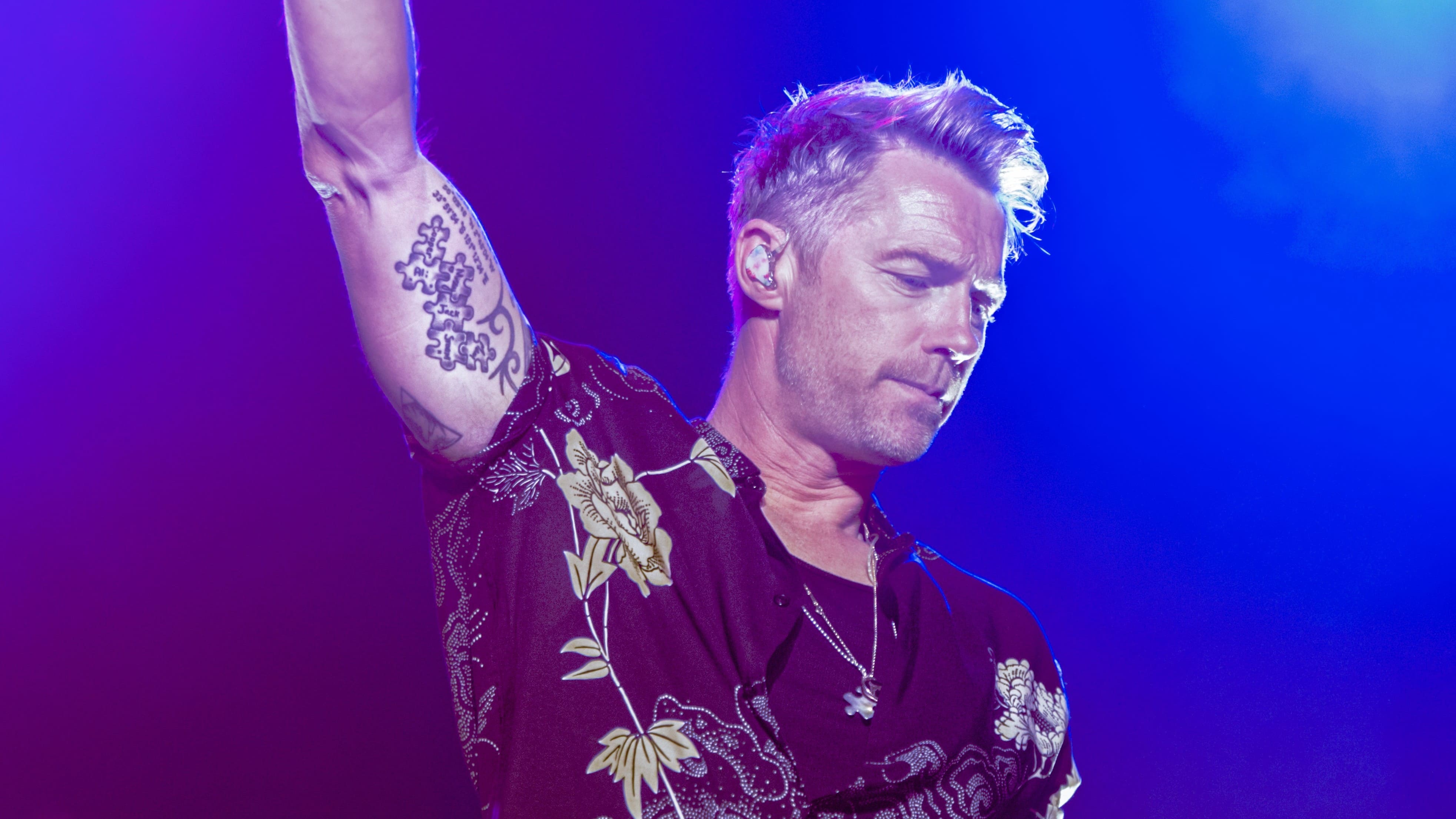 Person performing on stage with tattoos. Ronan Keating